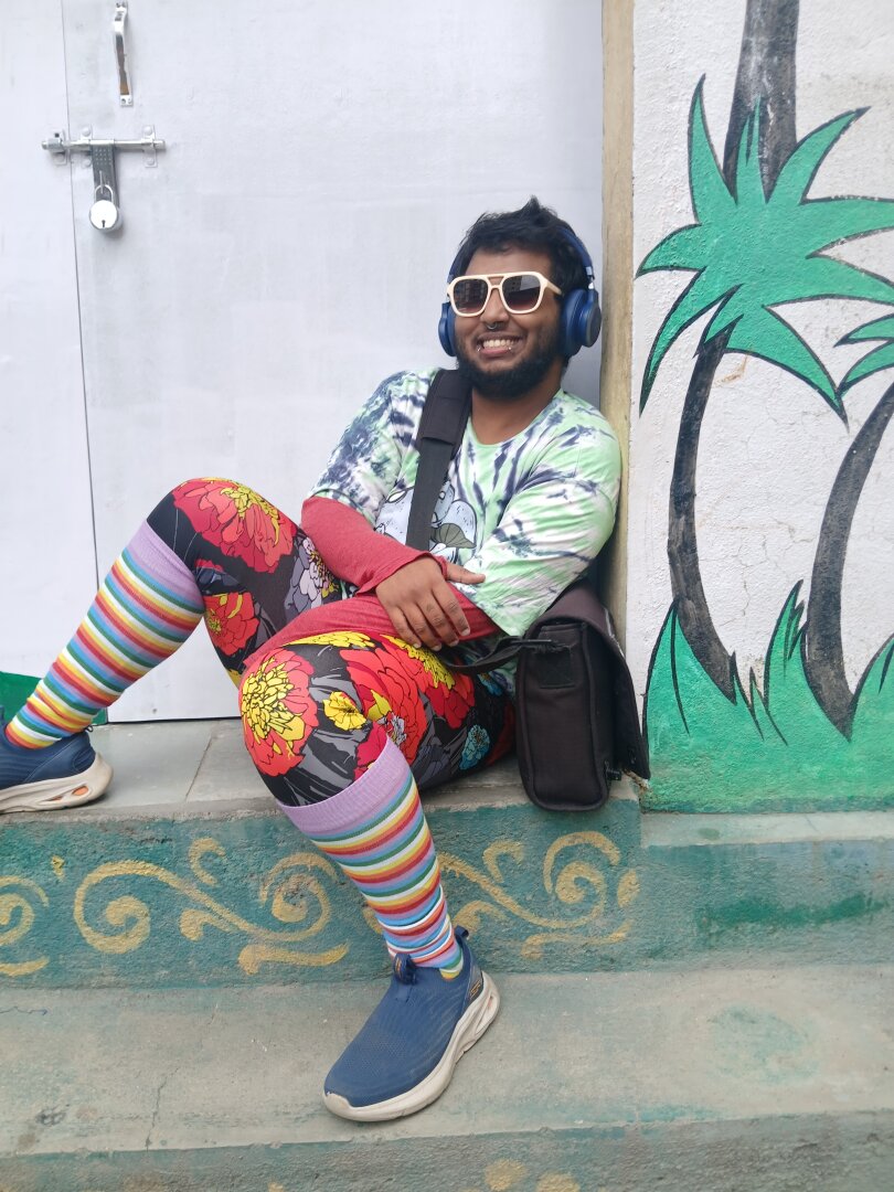 same person, outfit and place as before, but now they have turned to face the camera, and are smiling.